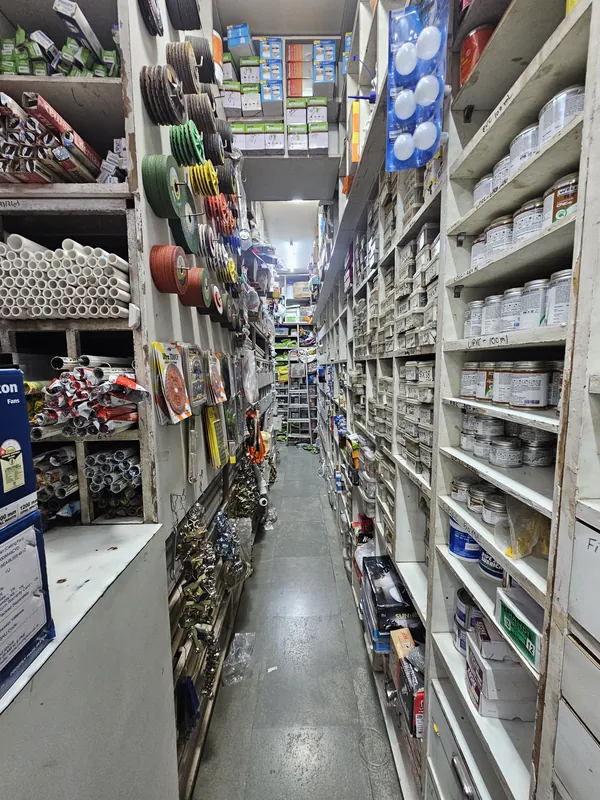 Stock aisle at Mahalaxmi Hardware and Electricals with cutting wheels, conduit pipe, solvent cement and fastener bins